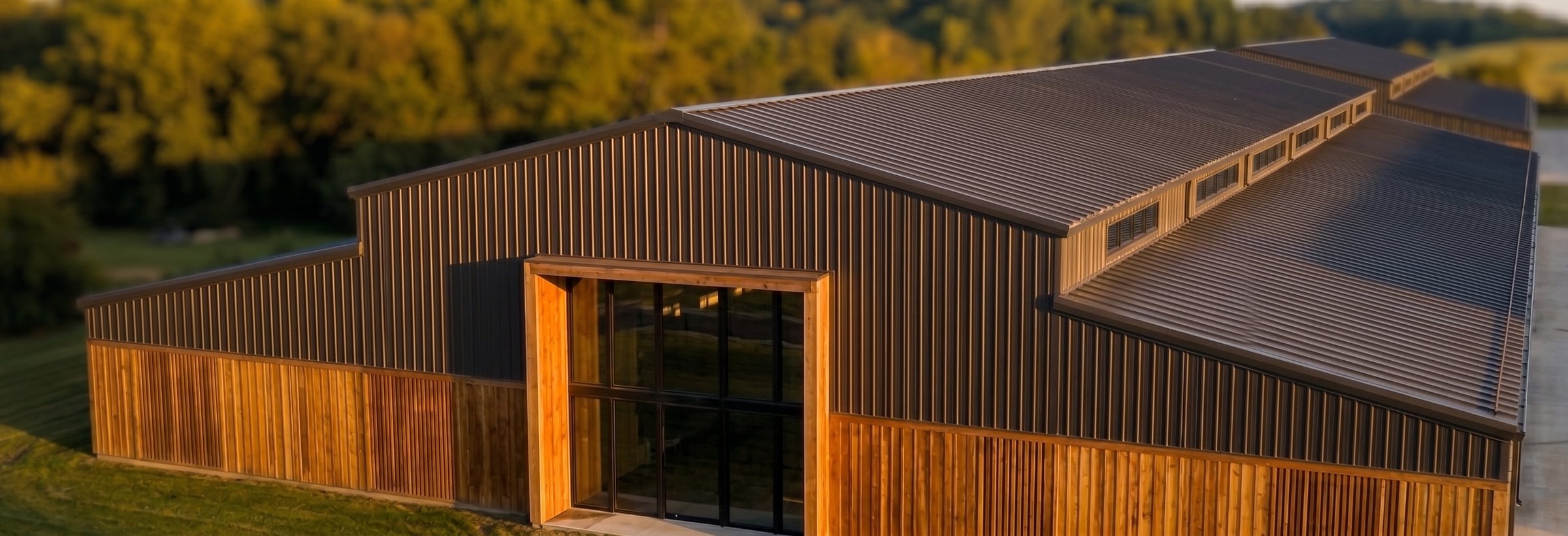 A low building in timber and dark metal, set in open land.